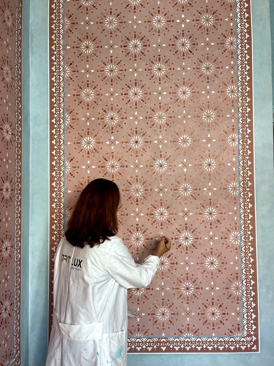 Artisan applying an arabesque pattern to a wall