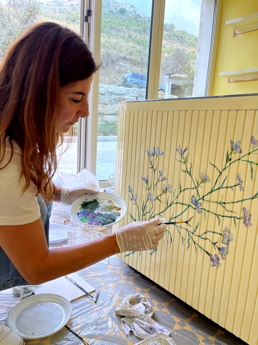 Artisan painting a botanical motif on a panel